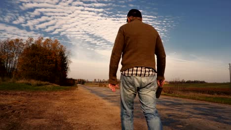 Hombre-en-la-máscara-de-Halloween-con-un-cuchillo-en-las-manos-caminando-por-el-borde-de-la-carretera