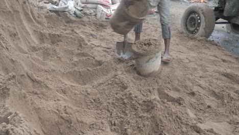 Mit-einer-Schaufel-Sand-in-einen-Eimer-zu-setzen-(Nahaufnahme)