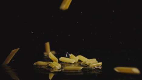 SLOW-MOTION:-Pasta-falls-in-water-in-dark-and-splashes-scatter-in-different-directions