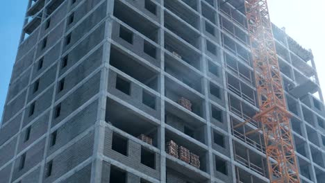 Multi-storey-under-construction-building-and-construction-crane-on-the-background-of-clear-sky.