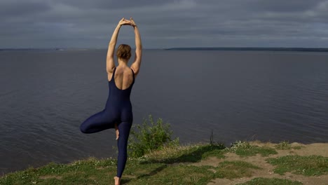 Yoga-Woman-Sportswear-gegen-See,-Ansicht-von-hinten