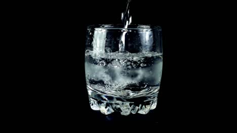 Wasser-in-einem-Glas-auf-einem-schwarzen-Hintergrund.-Slow-Motion.