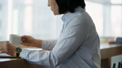 Mujer-bebiendo-café-y-trabajando-en-ordenador-portátil