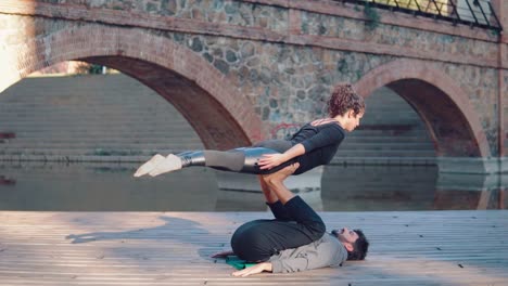 Schönes-paar-praktizieren-Acro-Yoga-am-Morgen