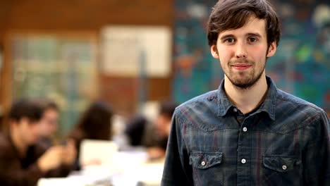 A-college-student-looks-at-the-camera-while-his-class-is-behind-him