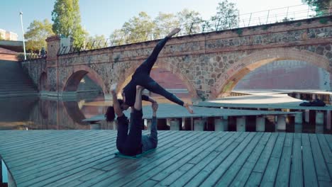 Schönes-paar-praktizieren-Acro-Yoga-am-Morgen