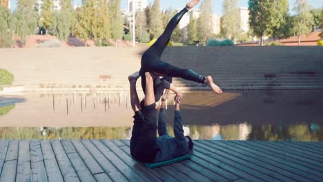 Schönes-paar-praktizieren-Acro-Yoga-am-Morgen