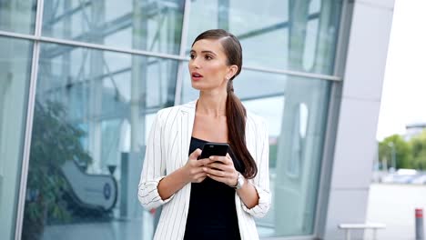 Beautiful-Business-Woman-Using-Phone-While-Walking-Near-Office