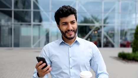 Hombre-de-negocios-guapo-con-teléfono-y-café-en-la-calle