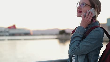 Cheerful-beautiful-young-girl-in-glasses-talking-on-her-smartphone.-Beatiful-lokation-in-Italia