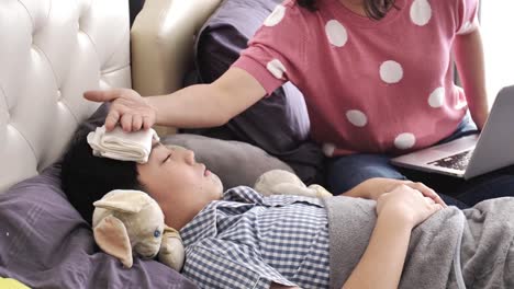 Madre-con-un-niño-intentar-trabajar-en-ordenador-portátil-en-casa,-un-niño-enfermo-estaba-acostado-en-la-cama-con-fiebre,-mama-es-cuidar-un-hijo-enfermo.-4k,-lenta.