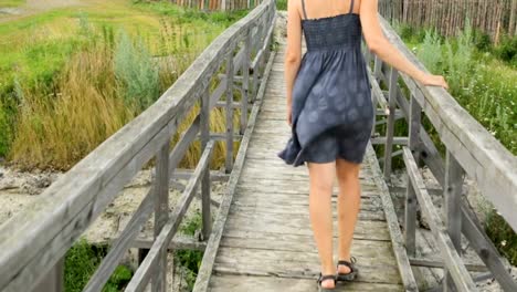 Woman-walking-along-old-wooden-bridge