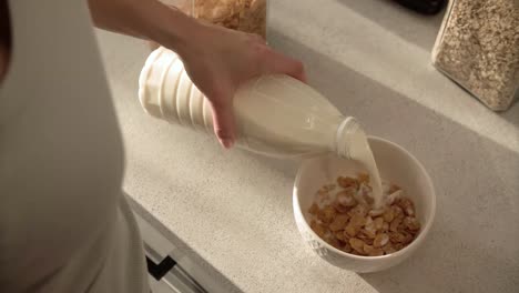 Gesundes-Frühstück.-Frau-Hand-gießen-Milch-in-Schüssel-mit-Flocken