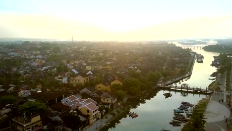 Vuelo-sobre-el-río-con-puentes-barcos-en-la-antigua-ciudad-de-Hoian