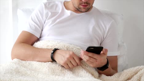 Man-using-smart-phone-lying-in-bed