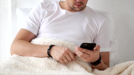 Mann-mit-Smartphone-im-Bett-liegend