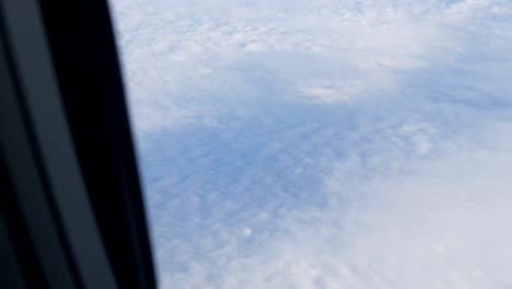 Wing-of-the-plane-through-the-porthole.-The-plane-flies-over-beautiful-air-clouds