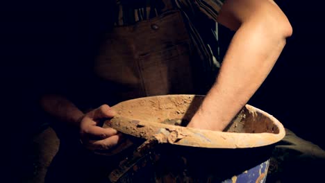 A-male-potters-hand-slowly-moves-inside-a-bucket-with-clay.