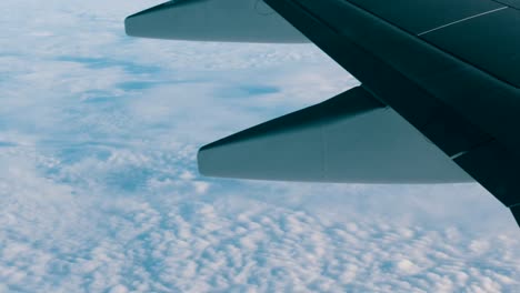 Blick-auf-die-Flügel-eines-Flugzeuges-im-Flug-über-schöne-Luft-Wolken