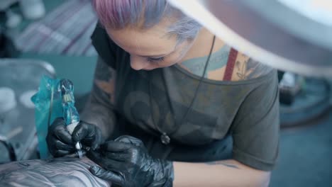 mujer,-un-artista-del-tatuaje,-hace-un-tatuaje-en-el-salón.