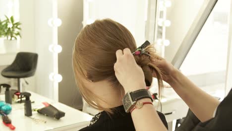 Hairstylist-using-hair-pin-during-preparation-to-female-haircut-in-hairdressing-salon.-Close-up-hairdresser-working-with-woman-client-in-beauty-studio