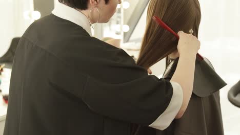 Hairdresser-combing-wet-hair-during-female-haircut-in-hairdressing-salon.-Close-up-hairdresser-making-female-haircut-in-beauty-salon