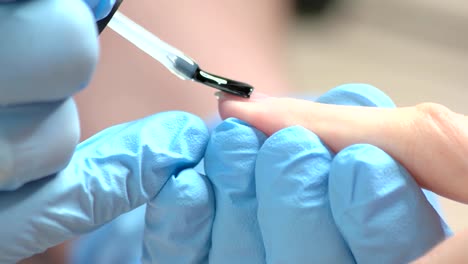 Applying-of-transparent-varnish-on-female-nails.