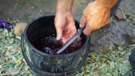 A-man-washes-a-bloody-knife-in-a-bucket-of-water.-Destruction-of-crime-evidence