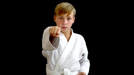 A-young-athlete-in-a-white-kimono-shows-a-punch-with-his-right-hand.-The-boy-holds-one-arm-around-the-waist,-and-the-other-moves-forward.-The-boy-has-blond-hair-and-dark-eyes