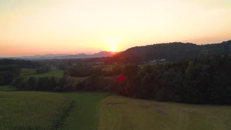 AERIAL:-Flying-over-the-empty-green-meadow-on-a-beautiful-sunny-summer-evening.