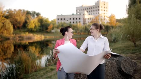 Dos-mujeres-arquitecto-e-Ingeniero-en-el-sitio-de-construcción-de-discutir-los-matices-según-planos-y-documentación-del-proyecto.