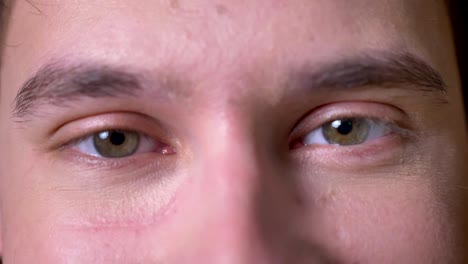 Close-up-focused-caucasian-male-is-removing-his-glasses-and-looking-directly-with-green-calm-eyes