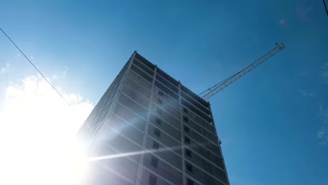 Multi-storey-under-construction-building-and-construction-crane-on-clear-sky-background.