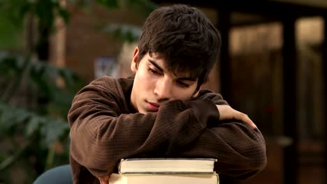 A-tired-college-student-rests-his-head-on-a-pile-of-text-books