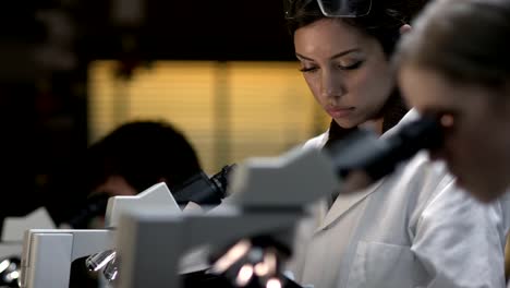 Students-in-a-laboratory-look-through-a-microscope-during-their-experiments