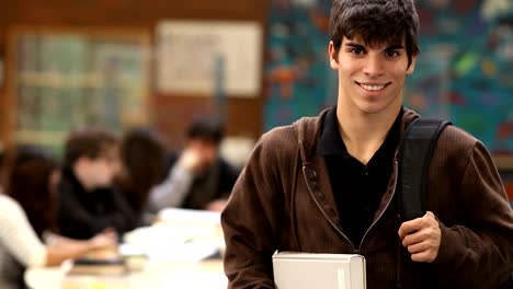 A-male-college-students-smiles-with-his-classmates-sitting-behind-him