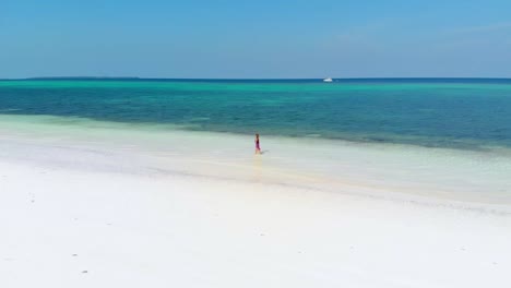 Aerial-slow-motion:-woman-walking-on-tropical-beach,-scenic-turquoise-water-and-white-sand,-Pasir-Panjang-Kei-Island,-Moluccas,-Indonesia,-paradise-travel-destination