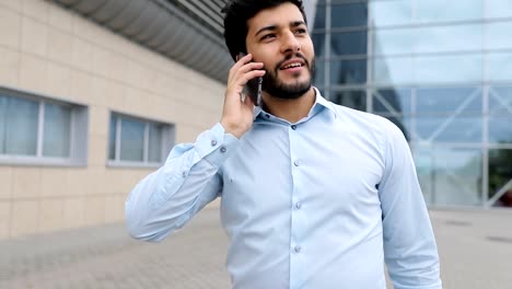 Hombre-guapo-hablando-por-teléfono-junto-a-la-oficina-al-aire-libre