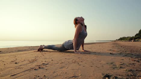 Aktive-junge-Frau-Stretching-und-Yoga-am-Strand-bei-Sonnenuntergang-zu-praktizieren.