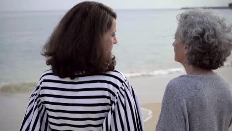 Mature-brunette-woman-narrating-something-to-senior-woman-on-seashore.