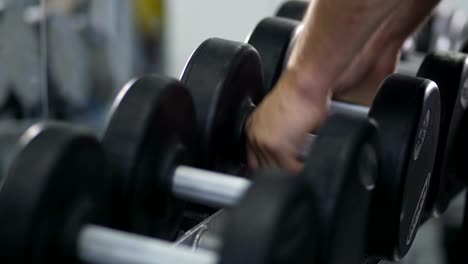 Close-up.-Male-hands-put-dumbbells-on-the-rack-4K-Slow-Mo