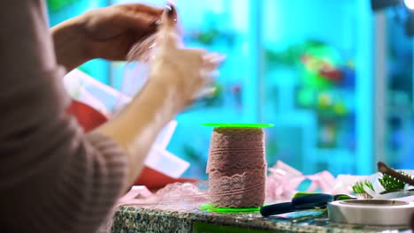 Woman-florist-cuts-the-ribbon-to-decorate-the-bouquet.-Hands-close-up.