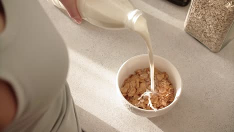 Gesundes-Frühstück.-Frau-Hand-gießen-Milch-in-Schüssel-mit-Flocken