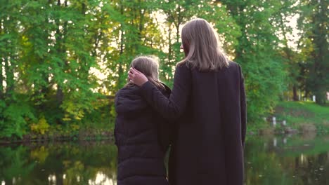 Frau-und-ihre-Tochter-stehen-in-der-Nähe-des-Teiches.