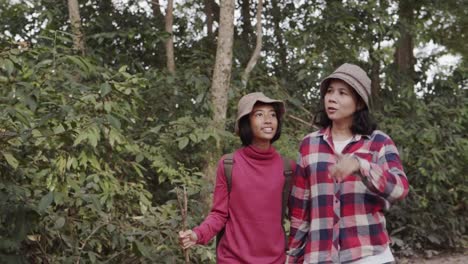 Medium-long-shot.-Asian-families-with-mother-and-daughter-holding-hand-while-walk-and-looking-in-the-morning-nature--in-forest-color-green.-The-concept-of-family-lifestyle-on-holiday