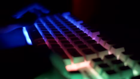 Männliche-Gamer-Tippen-und-Drücken-von-Tasten-auf-weißen-Gaming-RGB-Tastatur-in-dunklen-Raum