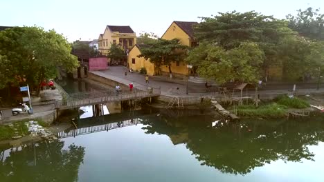 alte-Häuser-am-Wasser-mit-kleiner-Fußgängerbrücke-in-Hoian