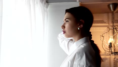 Young-woman-waiting-near-the-curtains-keeps-her-hair.