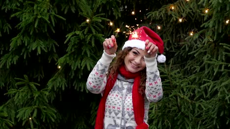 mujer-joven-en-el-fondo-del-árbol-de-Navidad-y-guirnaldas-con-sparklers.fun-y-saltos