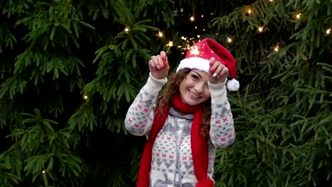 junge-Frau-auf-dem-Hintergrund-der-Weihnachtsbaum-und-Girlanden-mit-sparklers.fun-und-Sprünge